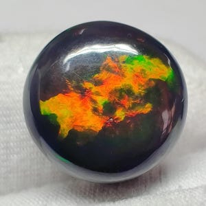 Cabujón de ópalo negro etíope de fuego, rojo, verde y multicolor, 9,4 cts (14 x 14 x 8 mm), forma redonda con gema de ópalo negro brillante con destellos múltiples.