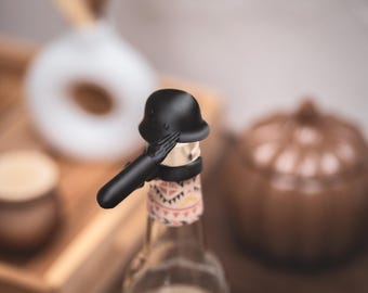 Stalen helm met arm als drankbeschermer voor bier, frisdrank en kleine champagneflesjes. Beschermt je drankje tegen insecten en drugs die gebruikt worden bij seksueel misbruik.