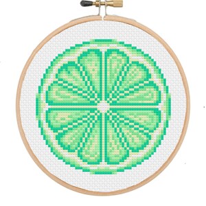Könnte beinhalten: Ein Kreuzstich-Stickrahmen mit einem grünen und weißen Limetten-Scheiben-Design.