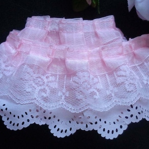 May include: Pink ruffled trim with a scalloped lace edge. The trim is made of a soft, sheer fabric and is perfect for adding a touch of elegance to any project.