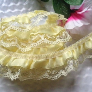 May include: Yellow ruffled lace trim with a satin ribbon. The trim is layered and has a delicate, feminine look.