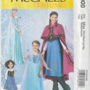 May include: A McCall's Costumes sewing pattern with illustrations of princess dresses. The pattern includes designs for a blue dress with floral accents, a light blue gown with a cape, and a pink cape with a black bodice and blue dress.