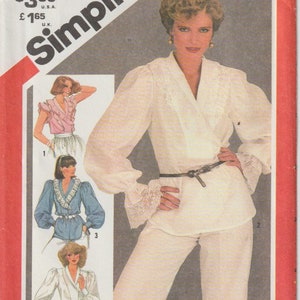 May include: Simplicity sewing pattern cover featuring a woman in a cream-colored wrap top and pants. The pattern includes illustrations of other blouse styles. The text on the cover reads "Simplicity" and "Medium Size 14-16".