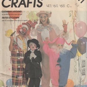 May include: A sewing pattern for three clown costumes. The pattern is for adults and children. The pattern is from McCall's Crafts and is number 2211. The pattern includes instructions for making a clown costume with a red and white checkered skirt, a pink and blue costume, and a black and white costume.