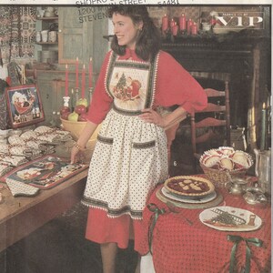 Puede incluir: Un conjunto de mesa de Navidad con un mantel rojo y blanco, un pastel rojo y blanco y una bolsa de mano roja y blanca. La mesa también tiene un delantal rojo y blanco, un plato rojo y blanco y un plato para pastel rojo y blanco. El texto "PATTERN/PATRON" está impreso en la parte inferior de la imagen.