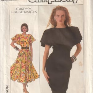 May include: Simplicity sewing pattern featuring two dress designs. One dress is a black, fitted sheath dress. The other is a colorful, patterned dress with a full skirt. The pattern includes the text "CATHY HARDWICK" and the number "8055".