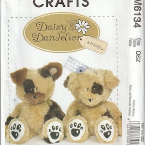 Könnte beinhalten: Ein Nähmuster für zwei Plüschtiere, Daisy und Dandelion. Das Muster ist von McCall's Crafts und ist für die Größe OSZ. Das Muster enthält Anweisungen zum Herstellen der Spielzeuge, die beide braun und weiß mit schwarzen Augen und Nasen sind.