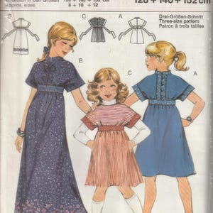 May include: A sewing pattern for a dress in three sizes: 128, 140, and 152 cm. The pattern includes instructions for making a dress with a high neckline, long sleeves, and a gathered skirt. The pattern is illustrated with two girls wearing the dress.