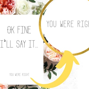 May include: A white card with the text "OK FINE I'LL SAY IT..." and "YOU WERE RIGHT" written on it. A gold circle with the text "YOU WERE RIGHT" is above the card with a yellow arrow pointing to the card.