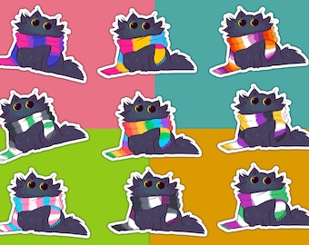 May include: Nine black cats wearing different colored scarves with pride flags. The scarves are in the colors of the bisexual, pansexual, genderqueer, lesbian, asexual, transgender, non-binary, and intersex pride flags.