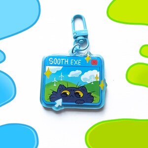 May include: A blue acrylic keychain with a cartoon cat peeking out from a computer screen. The screen displays a blue sky with clouds, windmills, and the text "SOOTH.EXE". The keychain has a blue clasp.
