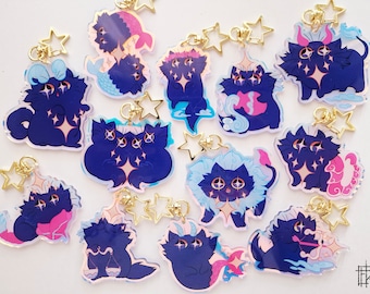 May include: Twelve colorful, glittery, black cat zodiac charm keychains. Each charm features a different zodiac sign with a black cat design. The charms are made of clear acrylic and have a gold-colored metal ring.