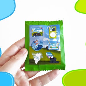 May include: A green packet featuring cartoon illustrations of a black cat in various scenes. The packet includes text and images of a cat in a fishbowl, a computer screen, and other playful designs. The words "SECRET RARE" are also visible.