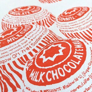 May include: Close-up of a red and white printed label with the text "MILK CHOCOLATE" and "INGREDIENTS: Mallow 38% (Sugar, Glucose Syrup, Shea Butter, Emulsifier (Soya Lecithin), Sodium Carbonate)."
