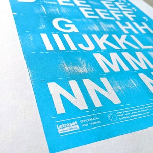 May include: A blue and white print of the alphabet, with the letters A through N, printed in white on a blue background. The print is numbered 1/200 and includes the text "Letraset SPACEMATIC heat resistant".