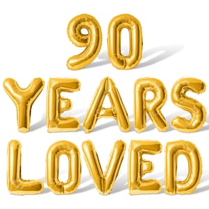 May include: Gold foil balloons spelling out "90 YEARS LOVED" on a white background. The number 90 is displayed above the text. The balloons are inflated and have a metallic sheen, ideal for a milestone birthday celebration.