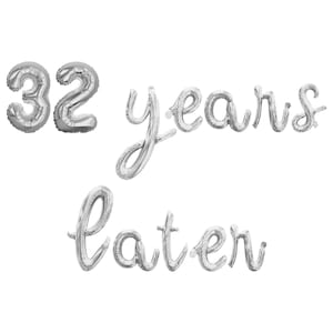 May include: Silver foil balloons spelling out "32 years later" against a white background. The number "32" is followed by the word "years" in cursive, and then the word "later" in cursive.