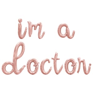 May include: Rose gold foil balloons spelling out "i'm a doctor".