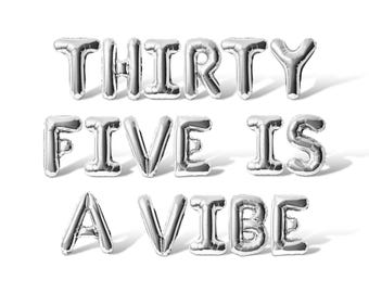 May include: Silver balloon letters spelling out "Thirty Five Is A Vibe".
