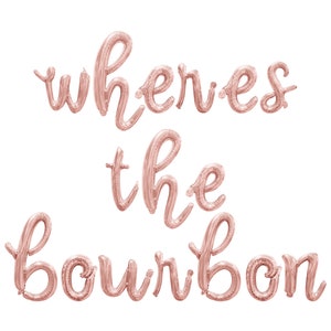 May include: Rose gold foil balloon letters spelling "where's the bourbon" in a cursive font.