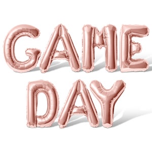 May include: Rose gold foil balloons spelling out "GAME DAY" in all caps.