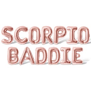 May include: Rose gold foil balloons spelling "SCORPIO BADDIE" on a white background. The balloons are inflated and have a metallic sheen. The letters cast a slight shadow, adding depth to the image. Perfect for a birthday or zodiac-themed party.