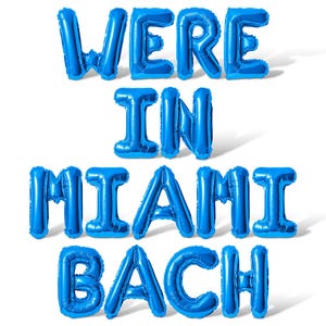 May include: Blue balloon letters spelling out "Were in Miami Bach" on a white background.