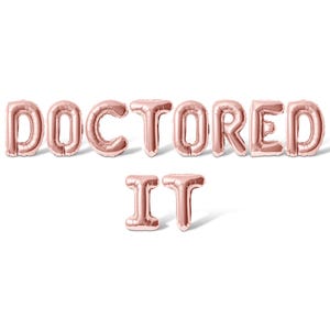 May include: Rose gold foil balloons spelling out "Doctored It" on a white background.