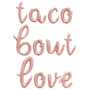 May include: Rose gold foil balloons spelling out "taco bout love" in a cursive font. The balloons are arranged vertically against a white background, perfect for a party or celebration.