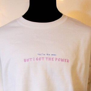 Può includere: Felpa bianca con il testo "You're the moon BUT I GOT THE POWER" in lettere rosa e blu.