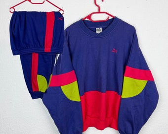 May include: A blue and red vintage Puma tracksuit with a yellow accent. The sweatshirt has a Puma logo on the chest.
