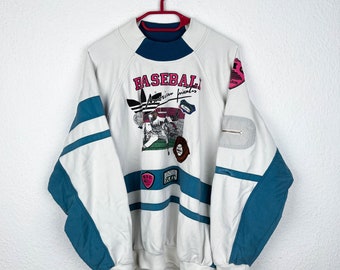May include: White sweatshirt with a blue and white striped design. The sweatshirt has a large graphic print of a baseball scene with the text "BASEBALL American friends" and the Adidas logo.