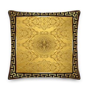 May include: Gold pillow with a black and gold Greek key border and a gold floral pattern.