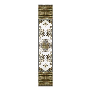 May include: A white table runner with a gold and black geometric pattern. The pattern features a repeating design of a circle with a Greek key border and floral motifs.
