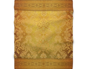 May include: A gold and brown patterned throw blanket with a damask design. The blanket has a border with a repeating geometric pattern.
