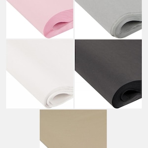 May include: Assortment of tissue paper in various colors. The image displays rolls of pink, gray, white, black, and tan tissue paper. The paper is neatly rolled, showcasing the different colors and textures.