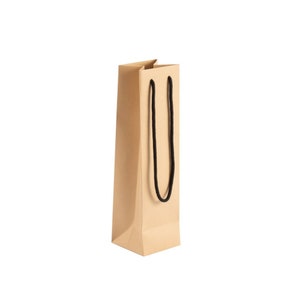 May include: A tall, rectangular brown paper gift bag with a black rope handle. The bag is made of a sturdy, folded paper material and is designed to hold a bottle. The bag is empty and stands upright against a white background.