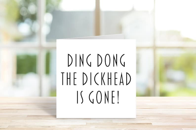 May include: A white card with black text that reads "Ding Dong The Dickhead Is Gone!"