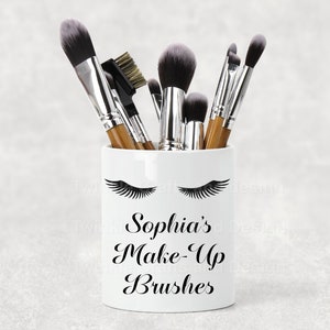 May include: White ceramic makeup brush holder with black eyelashes and the text "Sophia's Make-Up Brushes".