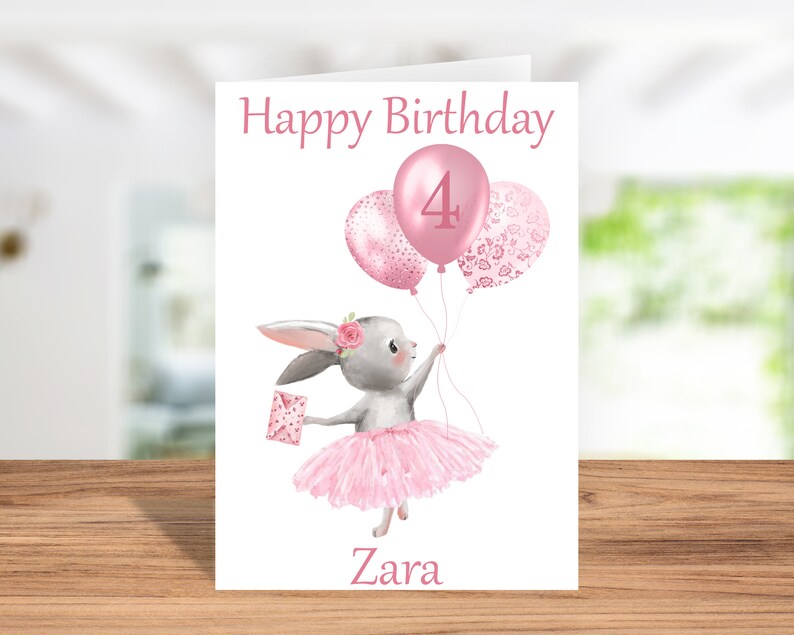 May include: A pink birthday card featuring a bunny wearing a pink tutu and holding pink balloons. The balloons have a pink number 4 and a pink floral pattern. The card reads "Happy Birthday" and "Zara".