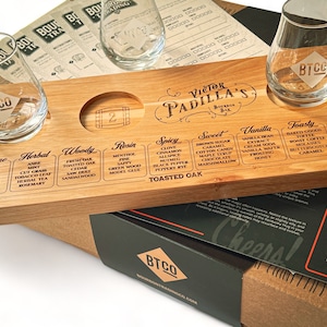 May include: A wooden bourbon tasting flight set with four etched glasses, a tasting board, and a box. The board is labeled "Victor Padilla's Bourbon Bar" and includes flavor profiles. The glasses are branded with "BTCO".