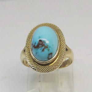 May include: A gold ring with a turquoise stone set in a textured oval bezel.