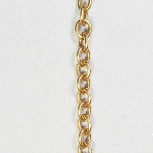 May include: Gold-toned chain with a heart-shaped charm. The charm has a smooth surface and appears to have engraved text. The chain is made of small, interlocking oval links and has a lobster clasp.