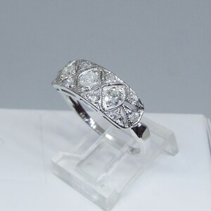 May include: A silver band ring with a geometric design featuring multiple small diamonds.