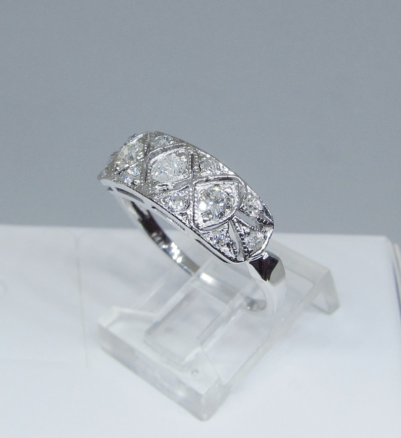 May include: A silver band ring with a geometric design featuring multiple small diamonds.