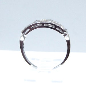 May include: A silver band ring with a row of small, clear gemstones set in a pave setting.