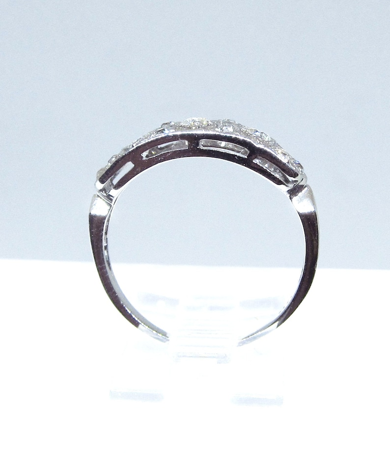 May include: A silver band ring with a row of small, clear gemstones set in a pave setting.