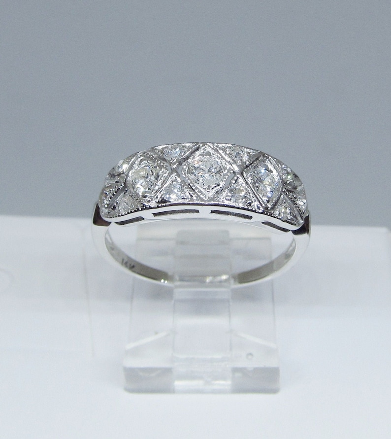 May include: A silver band ring with a row of diamonds set in a geometric pattern.