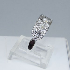 May include: A silver ring with a delicate design featuring multiple small diamonds set in a filigree pattern.