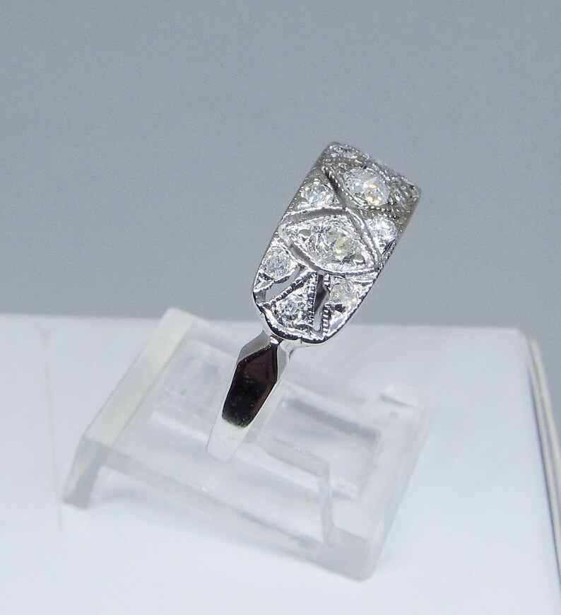 May include: A silver ring with a delicate design featuring multiple small diamonds set in a filigree pattern.